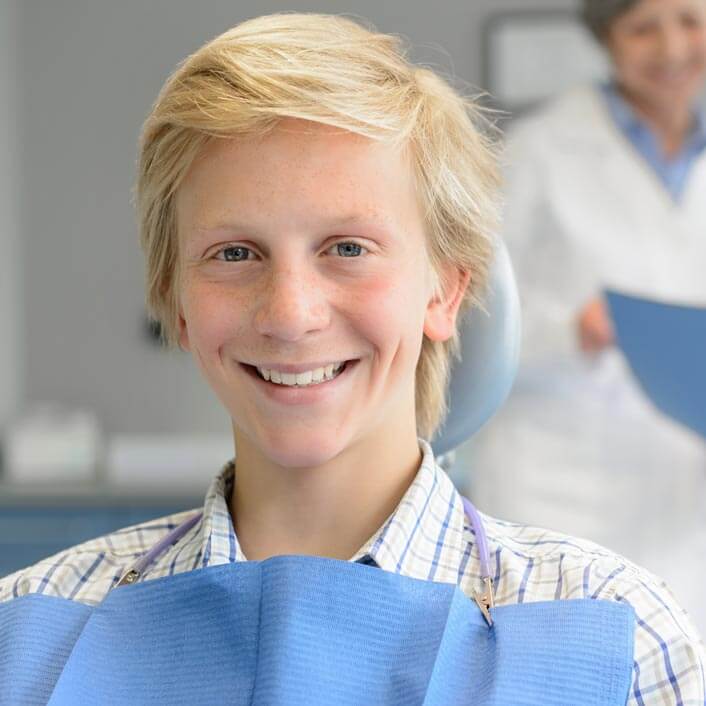 young man with platinum blond hair sitting in a dental chair smiling